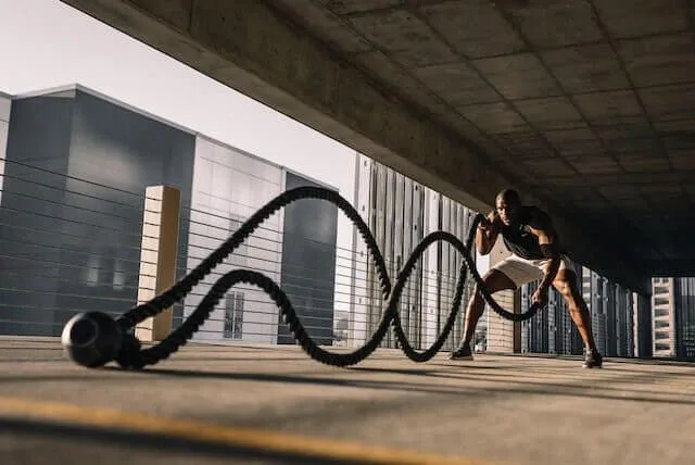 A man is working out with a battle rope.