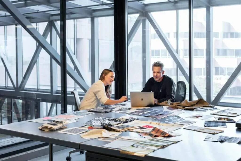 Two people collaborating on documentation and sharing knowledge at a desk in an office.