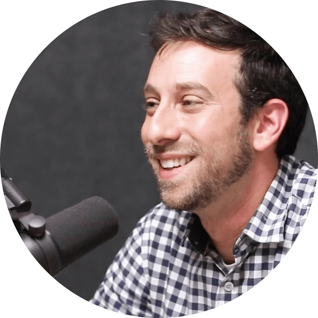 A man smiling while speaking into a microphone.