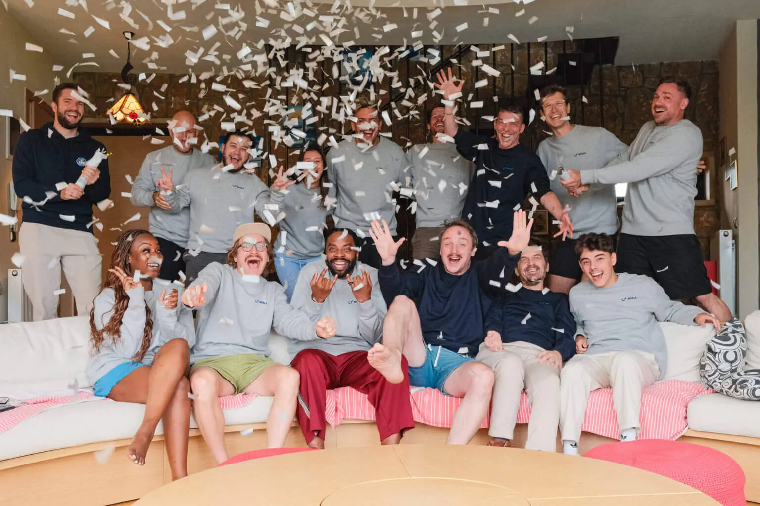 The Whale team in Whale sweaters on a sofa, cheering under falling confetti