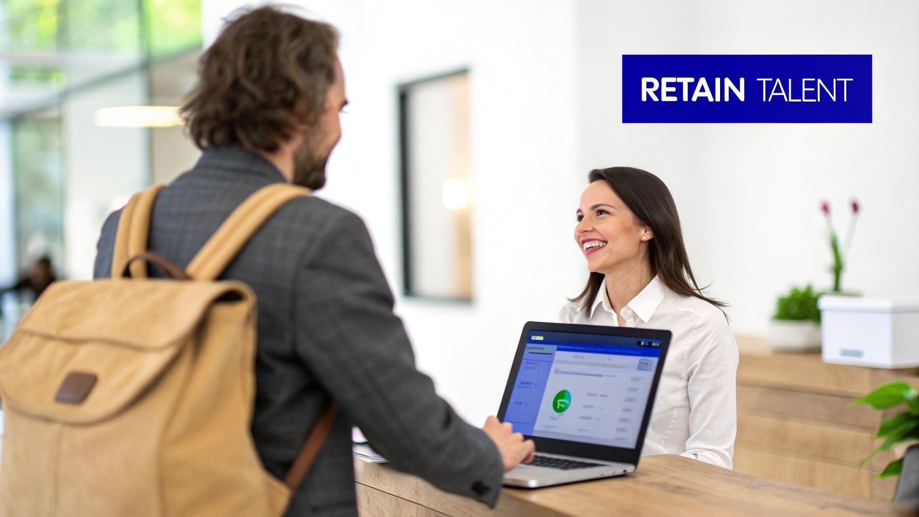 Smiling receptionist welcoming a new employee at a desk in a modern office with a laptop.
