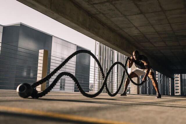 A man is working out with a battle rope.