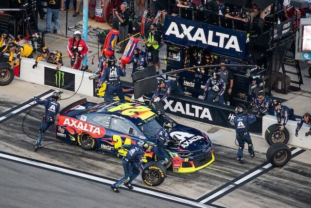 A pit crew is utilising employee training technology to work on a car.