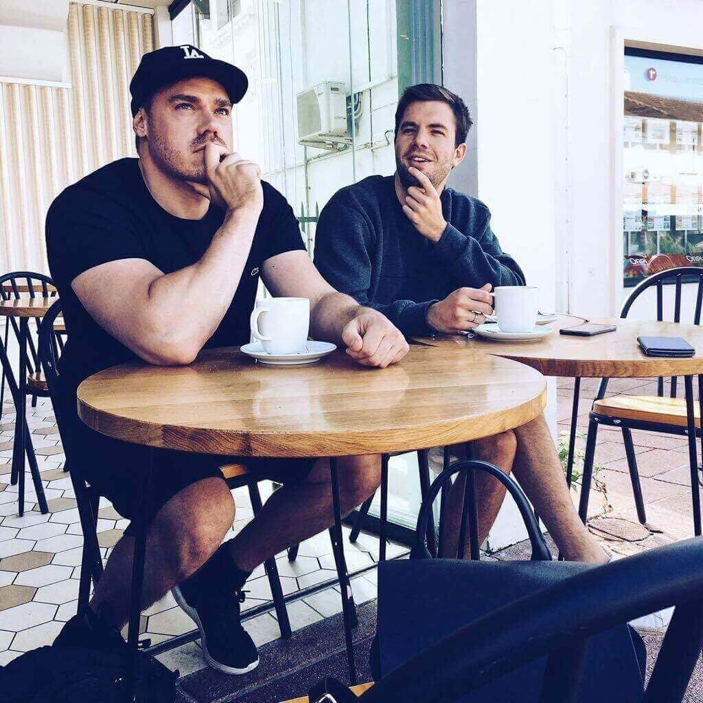 Two men sitting at a table drinking coffee.