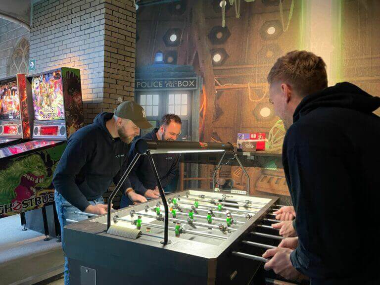 A group of people playing foosball in an arcade.