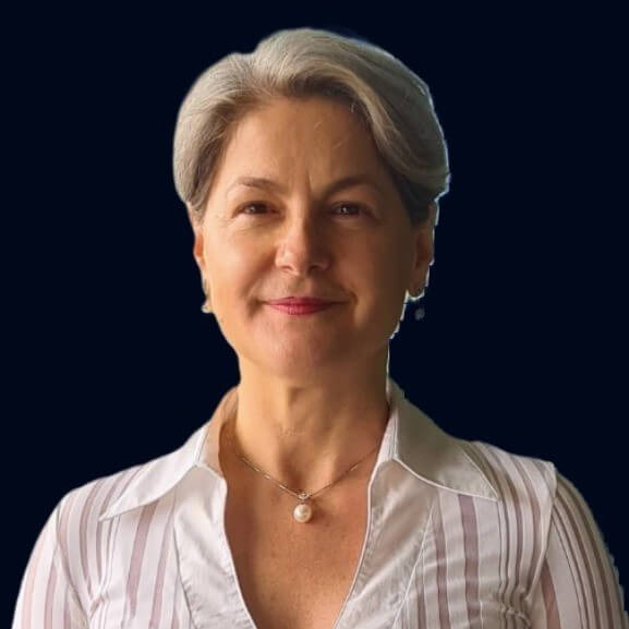 A woman with short gray hair and a slight smile, wearing a white blouse and pearl necklace, appears against a dark background, embodying the elegance one might bring to the process documentation of company SOPs.