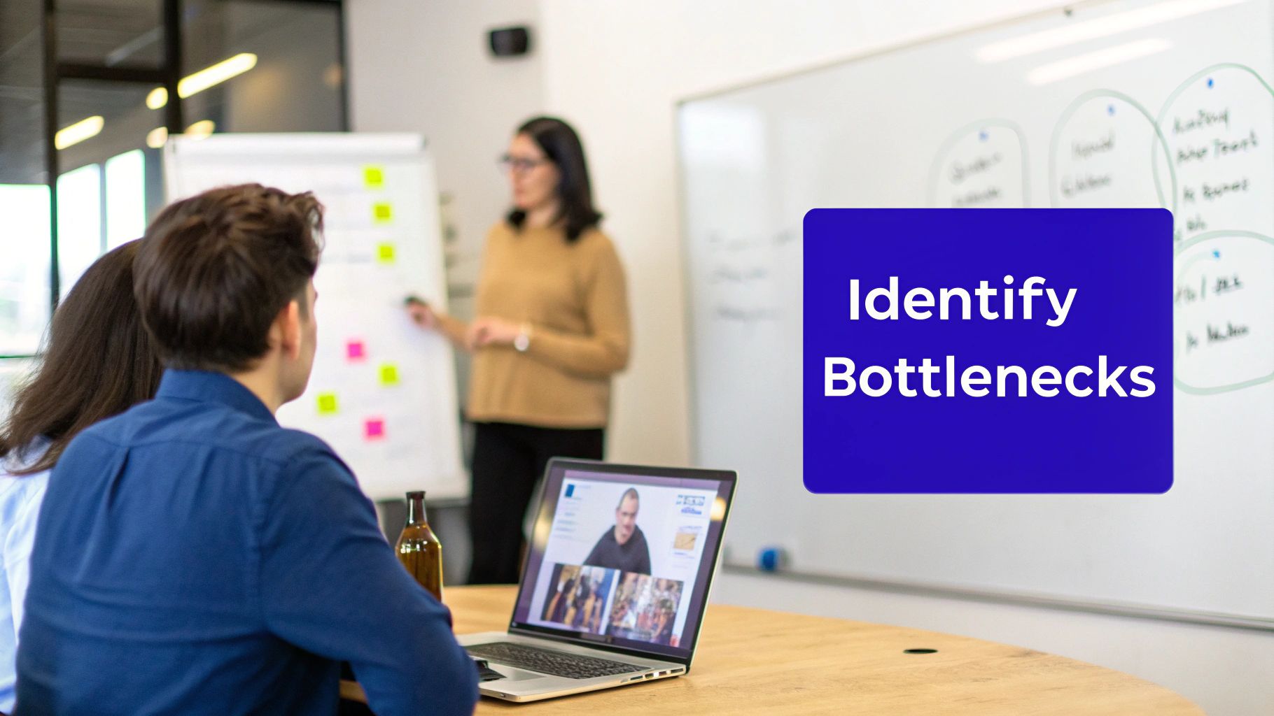 People in a business meeting, identifying bottlenecks, with a presenter and a laptop on the table.